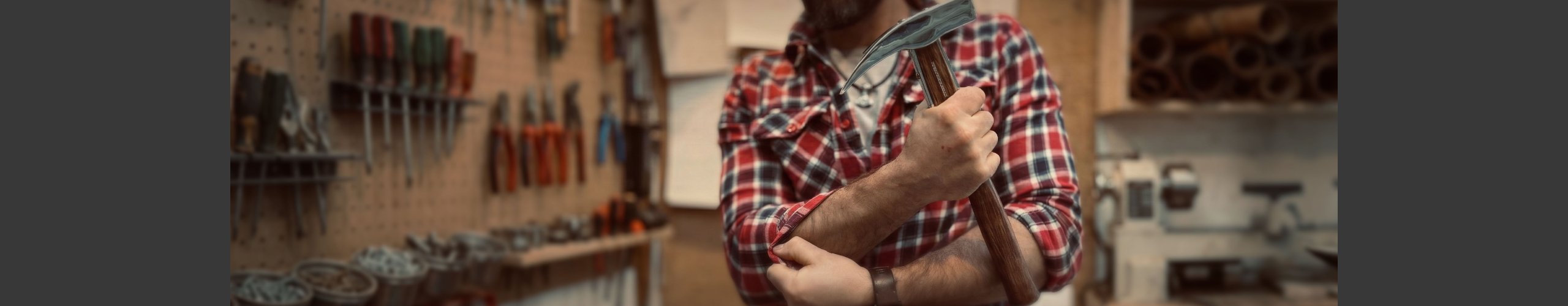 H�ndv�rker i ternet skjorte ruller �rmerne op i et lyst snedkerv�rksted med h�vleb�nk og v�rkt�j.